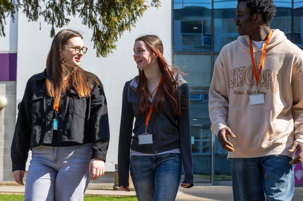 LANDSCAPE_3_STUDENTS_CLOSE_UP_WALKING_IN_FRONT_OF_BUILDING
