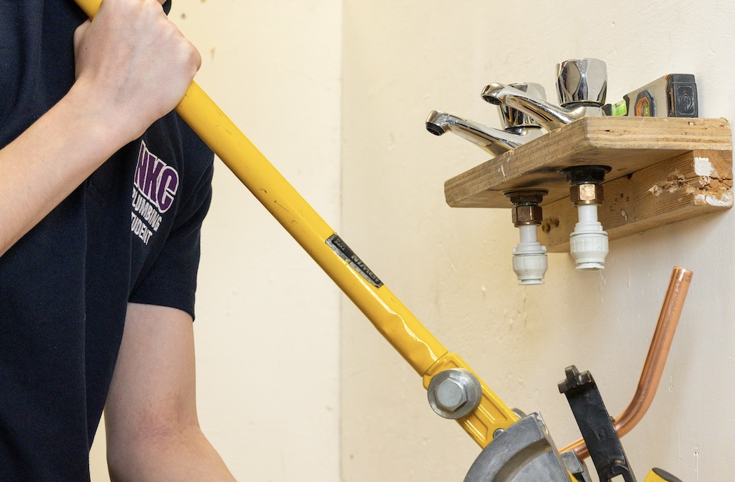 close up of student using a tool to fix a tap