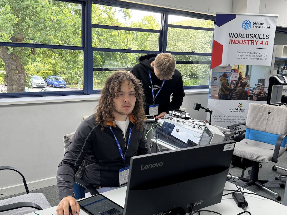 Engineering student at laptop with WorldSkills UK  banner behind